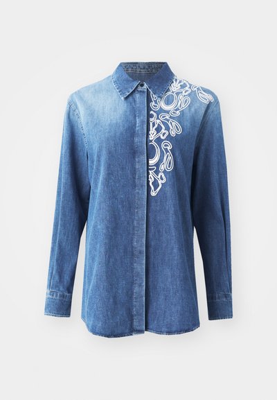 Camicia blu denim con maniche lunghe, chiusura frontale con bottoni e ricamo astratto bianco sulla spalla destra. Tessuto liscio con colletto classico.
