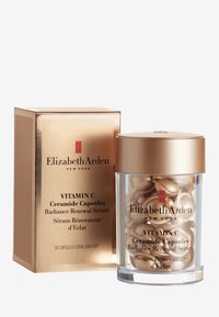 Barattolo oro e trasparente contenente capsule di ceramide color oro, confezionato in una scatola dorata con testo nero. Etichette in inglese e francese.