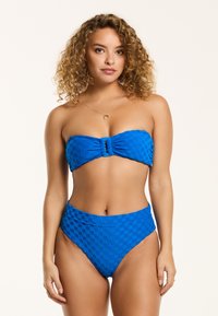 Kék bandeau bikini szett texturált kockás mintával. A top középen csomózott részlettel rendelkezik; magas derekú alsórész. Simább felület.