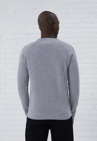 Sweatshirt gris à manches longues avec une texture unie, des manches raglan et des poignets côtelés. Conçu avec un col rond et un ourlet droit.