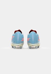Bottines de football bleues avec une finition texturée, arborant un logo blanc et rose, des accents rouges et des crampons métalliques sur la semelle extérieure.