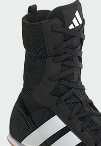 Czarny but sportowy z siateczkową cholewką, okrągłymi sznurówkami i białymi paskami po bokach. Teksturowane materiały z wysokim wsparciem kostki.