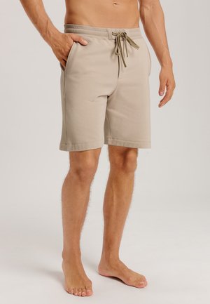 Beige shorts made of soft fabric with an elastic waistband, drawstring closure, and pockets on the sides. Smooth texture, knee-length fit.