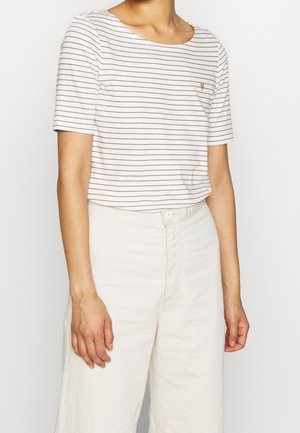 Osoba ubrana w biały krótki top z cienkimi brązowymi poziomymi paskami oraz kremowe spodnie z wysokim stanem i zapięciem na guziki.