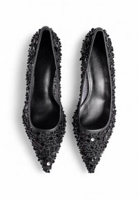 Zapatos de tacón negro con punta afilada cubiertos de lentejuelas y cuentas negras, con un interior de cuero suave y un diseño elegante.
