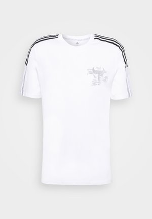 Camiseta de algodón blanca de manga corta, con rayas verticales negras en los hombros y un estampado gráfico gris en la parte frontal. Corte clásico, escote redondo.