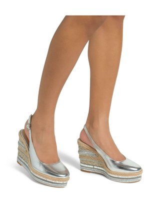Sandalias de cuña metálicas plateadas con una correa tipo slingback, que cuentan con una textura trenzada y detalles de yute en capas en la cuña, aseguradas con una hebilla.