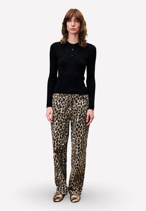 Zwarte geribbelde langemouwen top met kraag, gecombineerd met losse broek met luipaardprint. Model draagt metallic gouden ballet flats.