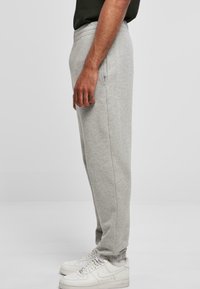 Szare dresowe spodnie wykonane z miękkiego materiału, o zwężanym kroju, z elastycznym pasem i bocznymi kieszeniami. W połączeniu z białymi sneakersami.