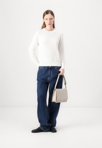Hvit genser med horisontale striper, blå vide jeans og en lys grå håndveske. Svart sko fullfører antrekket.