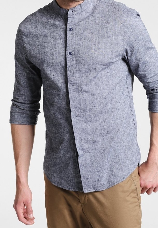 Camisa de algodón azul jaspeado con cuello mao, mangas largas y una tapeta frontal abotonada. Textura suave con botones en contraste.