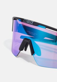 Lunettes de soleil avec un grand verre dégradé passant du violet au bleu, monture noire et un logo très visible sur le dessus.