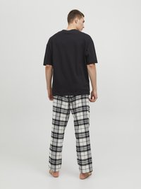 Svart bomullströja och rutiga pyjamasbyxor i vitt, svart och grått, med en lös passform och mjuk textur.