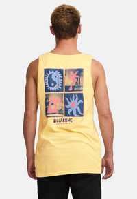 Top sin mangas amarillo con un diseño gráfico en la parte posterior, que incluye cuatro impresiones cuadradas coloridas con motivos estilizados de sol y olas.