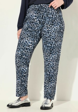 Blauwe en grijze dierenprint broek met een trekkoord in de taille, taps toelopende pijpen en een gladde stoftextuur. Gecombineerd met zilveren loafers.
