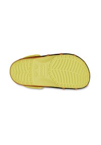 Calzature Crocs con suola gialla strutturata, caratterizzata da un motivo del battistrada e accenti arancioni. Il materiale sembra gommoso e resistente.