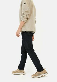 Beżowa polarowa kurtka, ciemnoniebieskie dżinsy i jasnobrązowe trampki; codzienny strój z kontrastującymi fakturami i kolorami.