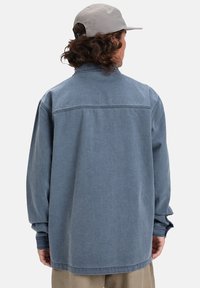 Jeansjacke in Hellblau mit einem lockeren Schnitt, langen Ärmeln und einer Yoke-Detail über dem Rücken. Mit lockeren Bündchen akzentuiert.