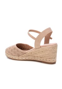 Sandalia de cuña beige con parte superior de cuero que presenta patrones florales cortados con láser, correa ajustable en el tobillo y tacón envuelto en yute trenzado.