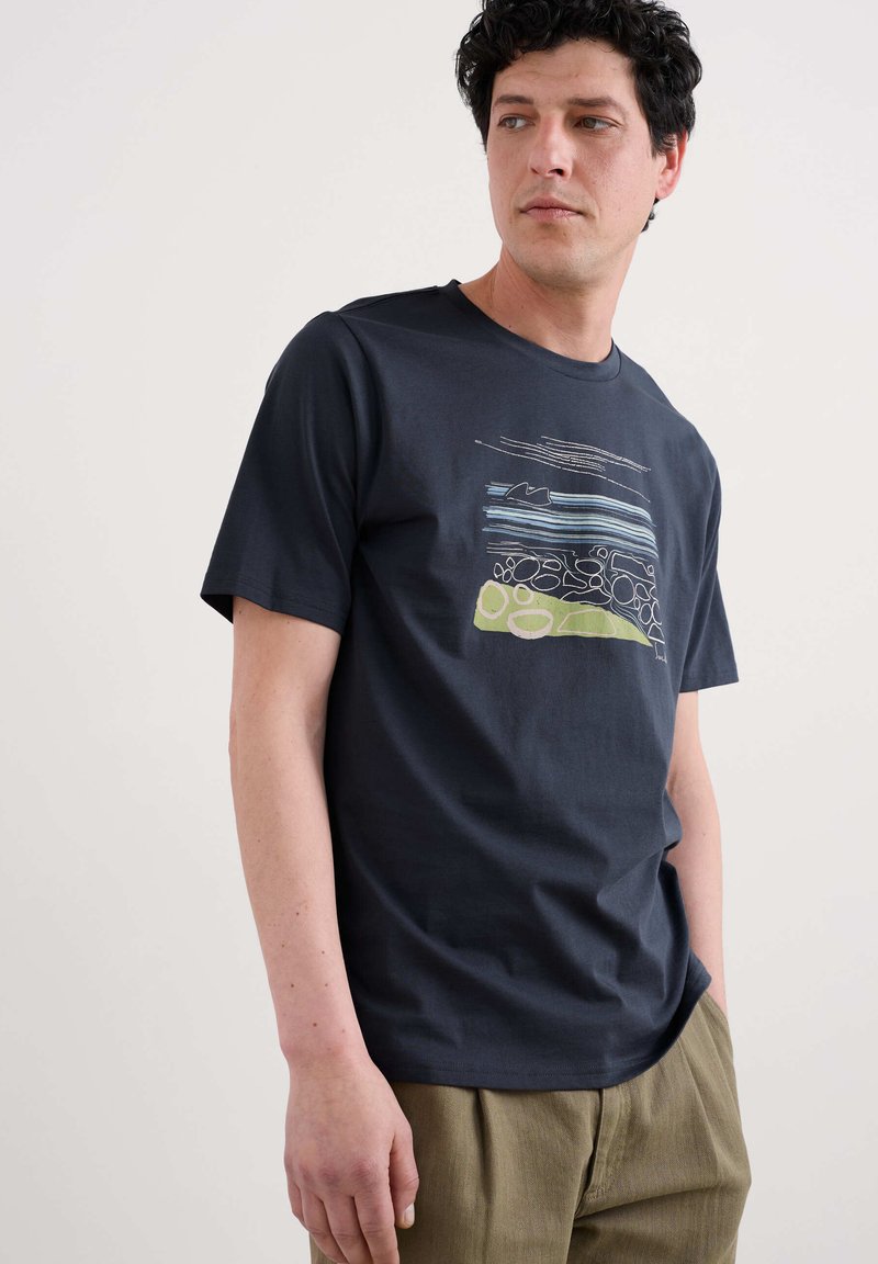 Camiseta de algodón en color azul marino con un colorido diseño abstracto que incluye líneas y formas. Cuello redondo y mangas cortas. Tejido texturizado.
