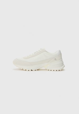 Białe niskie sneakersy z masywną podeszwą i sznurowaniem z przodu, z logo "ck" po stronie pięty.