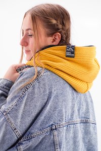 Knitted yellow hood worn over a gray jacket, featuring a textured pattern and a tag with "EST. MMXIII" on the back.
