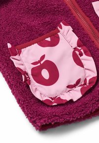 Fleecejacka i djup magenta med en rosa ficka som har en volangkant och äppelmönster. Mjuk textur med dragkedja.