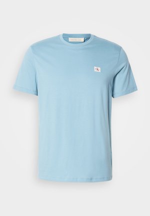 Lichtblauwe katoenen T-shirt met korte mouwen, ronde halslijn en klein logo-opdruk op de linkerkant van de borst. Glad textuur en eenvoudig ontwerp.