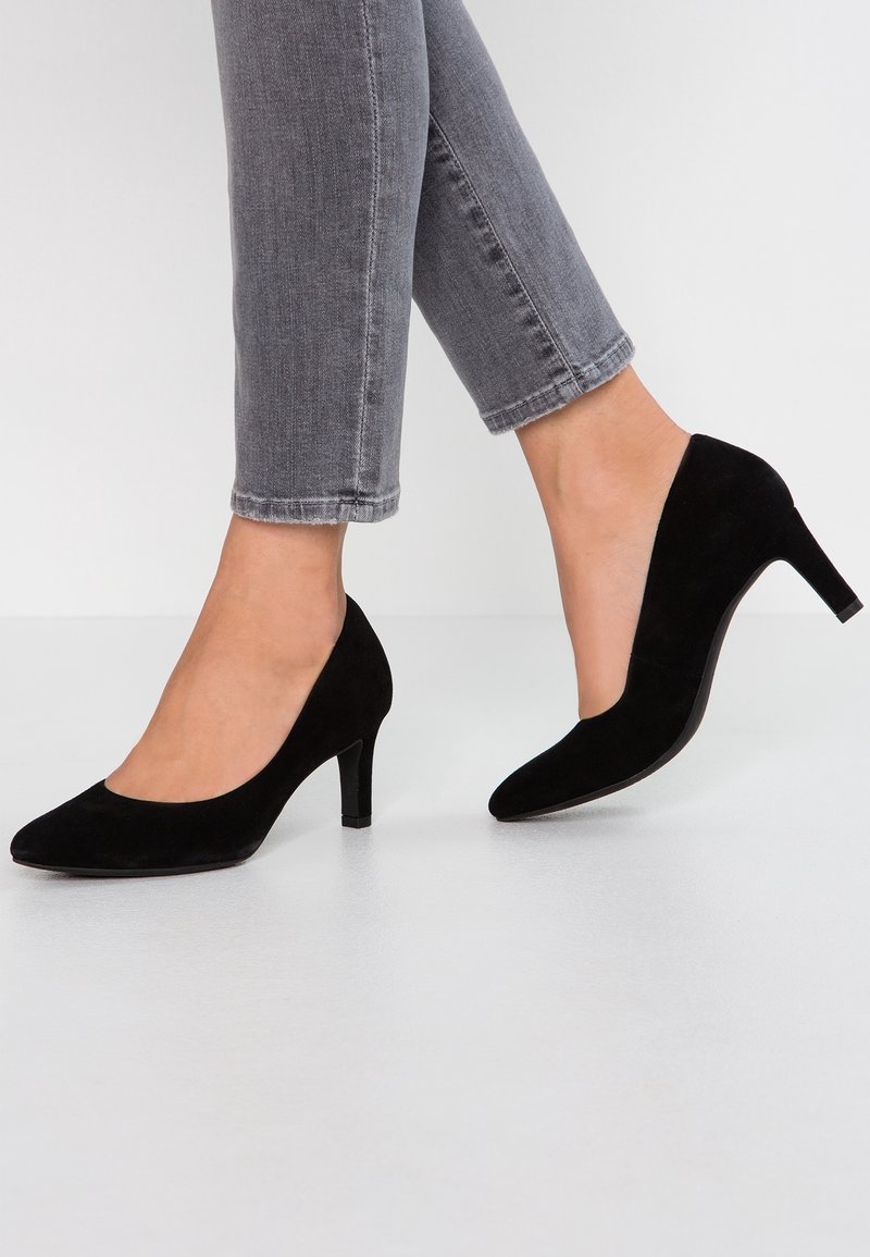 Escarpins en daim noir avec un bout pointu, dotés d'un talon bloc de 7 cm et d'une texture lisse. Associés à un jean gris coupé court.