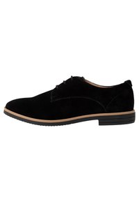 Chaussures oxford en suède noir avec une semelle plate noire et beige. Les caractéristiques incluent un bout arrondi, deux œillets et de simples détails de couture.