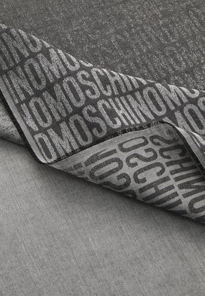 Mustaa ja harmaata kangasta, jossa on hienovarainen rakenne, ja tulostettu logo rohkeilla kirjaimilla. Reuna on tarkasti viimeistelty.