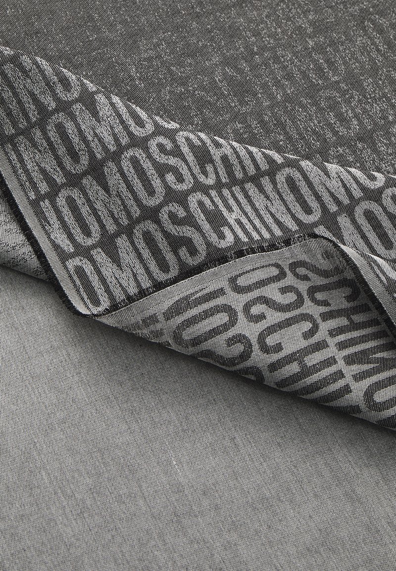 Material negru și gri cu o textură subtilă, având un logo imprimat cu litere îndrăznețe. Marginea este finisată cu precizie.