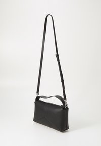 Sac à épaule en cuir noir de forme rectangulaire, avec une fermeture à glissière, une bandoulière réglable et des détails de couture géométriques.