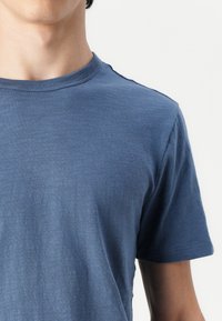 Blauwe crew neck t-shirt gemaakt van een gestructureerde stof. Korte mouwen met een nauwsluitende pasvorm. Glad, minimalistisch ontwerp zonder patronen of versieringen.