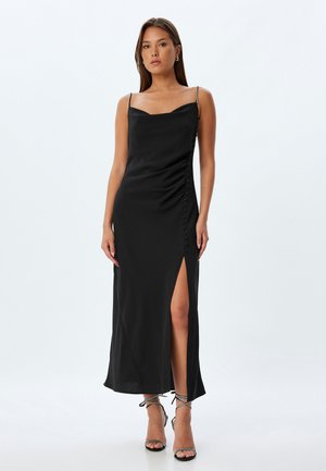 Zwarte satijnen maxi-jurk met een getailleerde silhoutte, een uitsnijding aan de zijkant en decoratieve knopen aan de linkerkant. Heeft dunne bandjes en een gladde textuur.