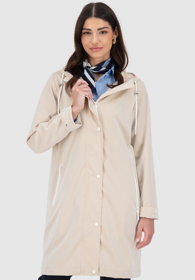 Cappotto impermeabile beige con cappuccio, dotato di chiusura lampo frontale, bottoni a pressione e tasche laterali. Texture liscia, design leggero.