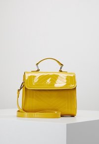 Borsa a mano gialla in vernice con design strutturato, texture a motivo chevron, manico superiore e tracolla regolabile. Accenti in metallo argentato.