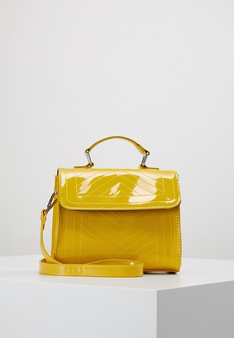 Borsa a mano gialla in vernice con design strutturato, texture a motivo chevron, manico superiore e tracolla regolabile. Accenti in metallo argentato.
