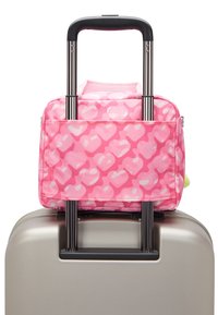 Rosa mönstrad Duffelväska som ligger ovanpå en silverfärgad resväska, med ett utdragbart handtag och två vertikala stödstag. Mjukt tygmaterial.