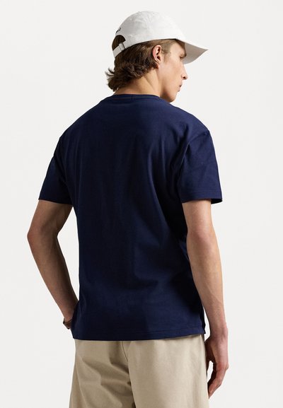 Marineblauwe katoenen t-shirt met korte mouwen, ronde hals en een ontspannen pasvorm. Draagt met een witte pet. Minimalistisch ontwerp, geen zichtbare patronen.