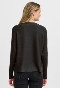 Zwarte geribbelde lange mouw trui met een ronde halslijn en een relaxte pasvorm, voorzien van een subtiele textuur en een gebogen zoom.