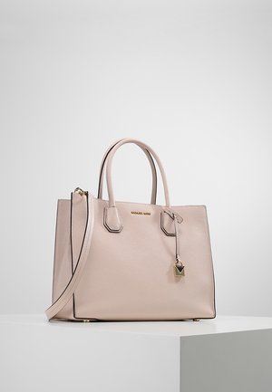 Světlá růžová kožená kabelka s dvojitými rukojetmi, odnímatelným ramenním popruhem a zlatým přívěskem ve tvaru zámečku na čistě bílém povrchu.