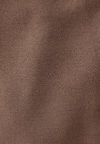 Texture de tissu brun avec un motif de tissage diagonal subtil et un éclairage doux montrant de légers plis.