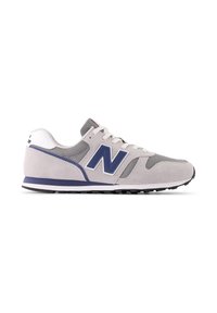 Scarpa sportiva in suede grigia con accenti blu navy, pannelli laterali in rete, lacci bianchi e suola in gomma nera. Presenta un grande logo "N" sul lato.