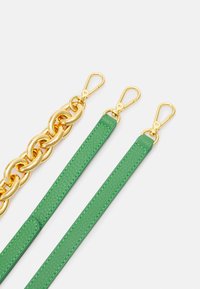 Catena in metallo dorato e due cinturini in pelle verde con chiusure dorate, disposti affianco su uno sfondo bianco.