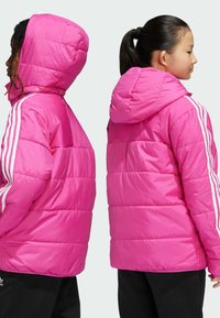 Růžová péřová bunda s kapucí, která má bílé pruhované akcenty na rukávech, prošívanou texturu a volný střih. Zadní pohled ukazuje načechranou siluetu.