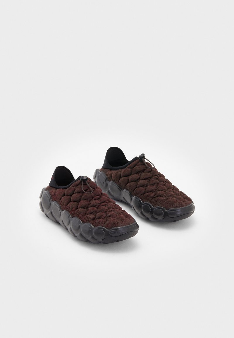 Dark red, quilted fabric sneakers with a textured, bulbous black sole and elastic laces for a secure fit. Low-profile design.