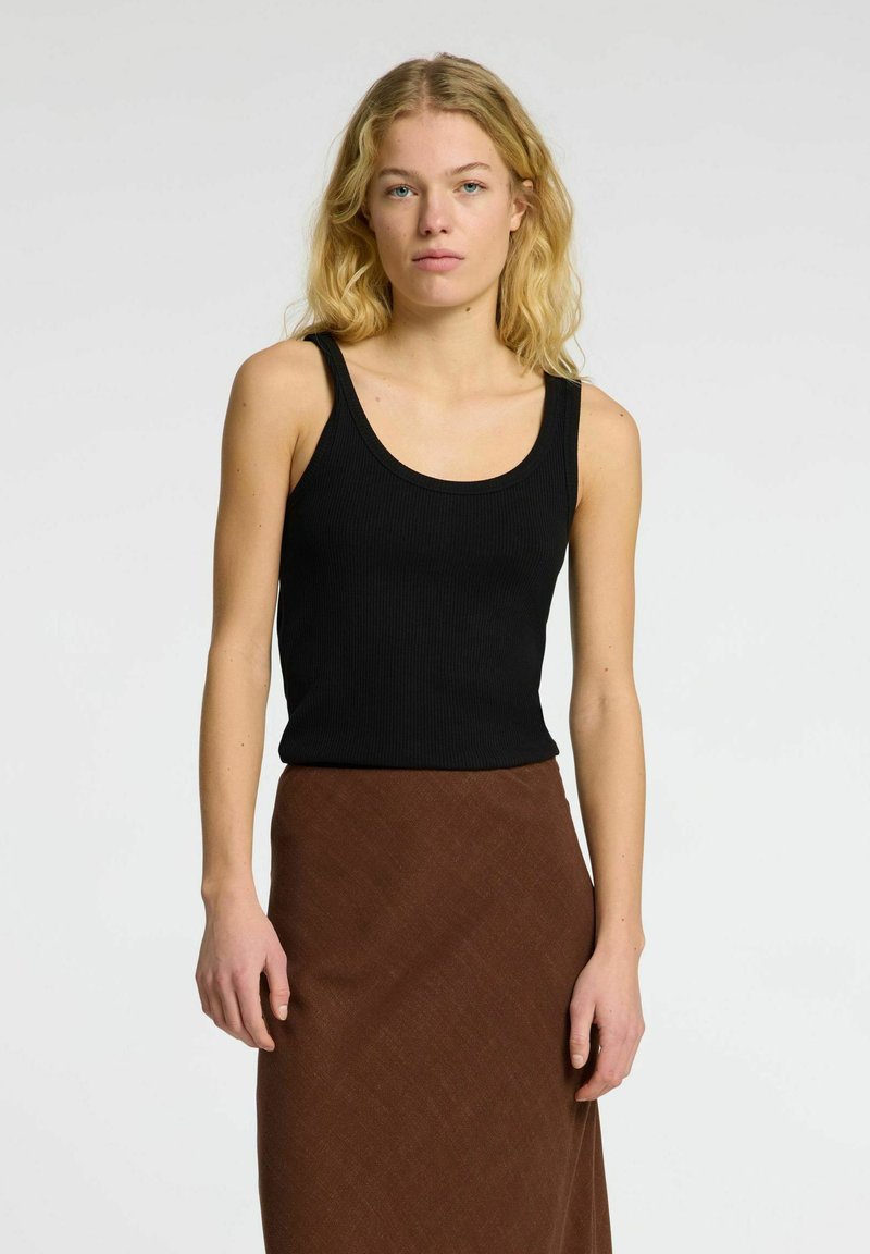 Top sin mangas negro de canalé con escote en forma de barco, combinado con una falda marrón texturizada. La tela tiene un acabado suave, diseñada para un ajuste ceñido.