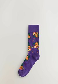 Purple sock with orange and green parrots and scattered orange seeds pattern on a light background.
