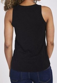 Czarna prążkowana bluzka na ramiączkach z okrągłym dekoltem, bez rękawów i dopasowanym krojem, zestawiona z ciemnymi dżinsami.